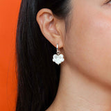 On model ruyi earrings with ruyi shaped charms outlined in silver and filled with pearlescent white enamel.