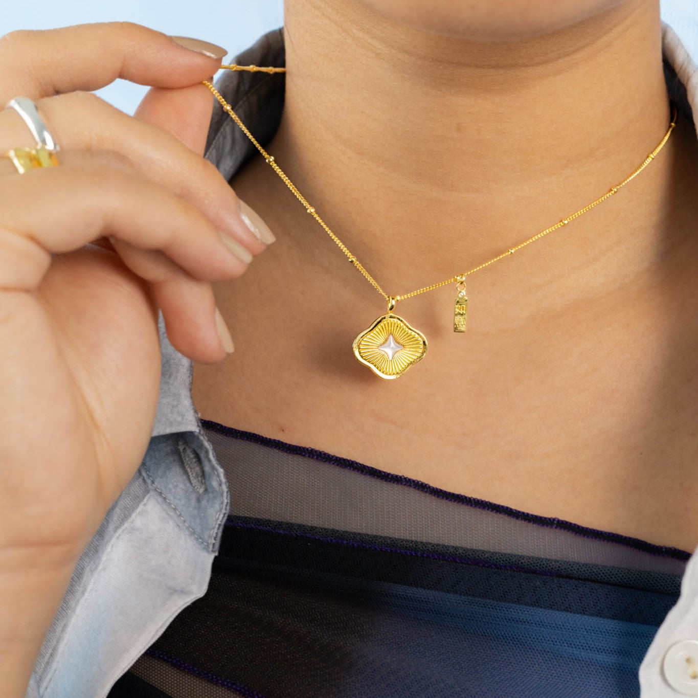 Modern Chinese necklace with a ruyi silhouette, sunray texture, mother of pearl star, and ruyi tag with cubic zirconia for good luck. Comes in 14k gold vermeil.