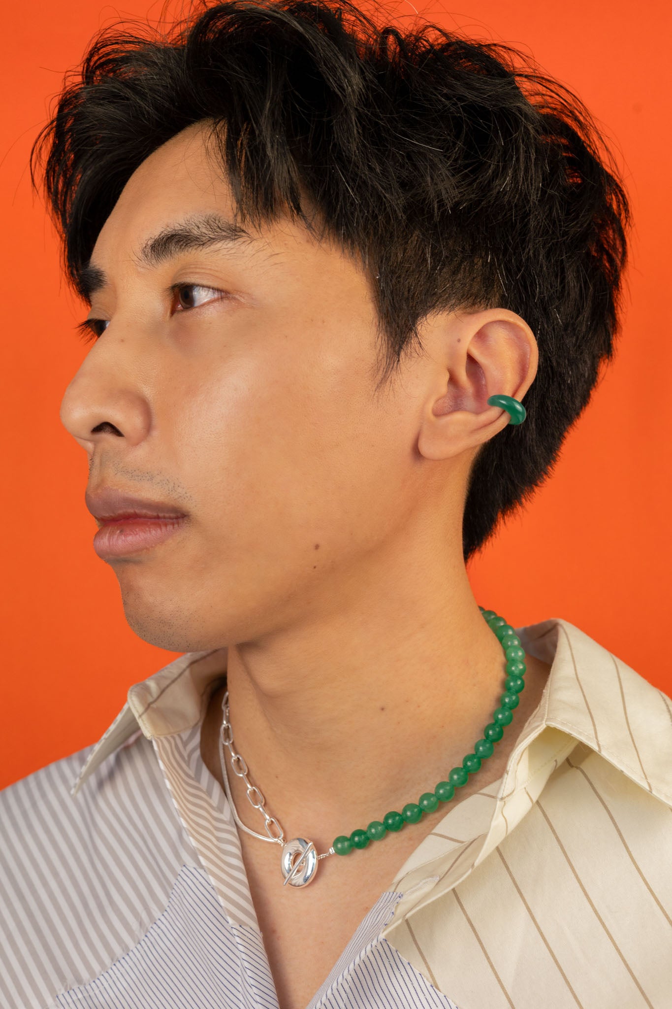 A man wearing the Heaven and Earth necklace; a modern Chinese jewelry piece that can be worn as a necklace or taken apart to form two bracelets.
