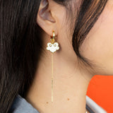 On model ruyi earrings with ruyi shaped charms outlined in gold and filled with pearlescent white enamel.