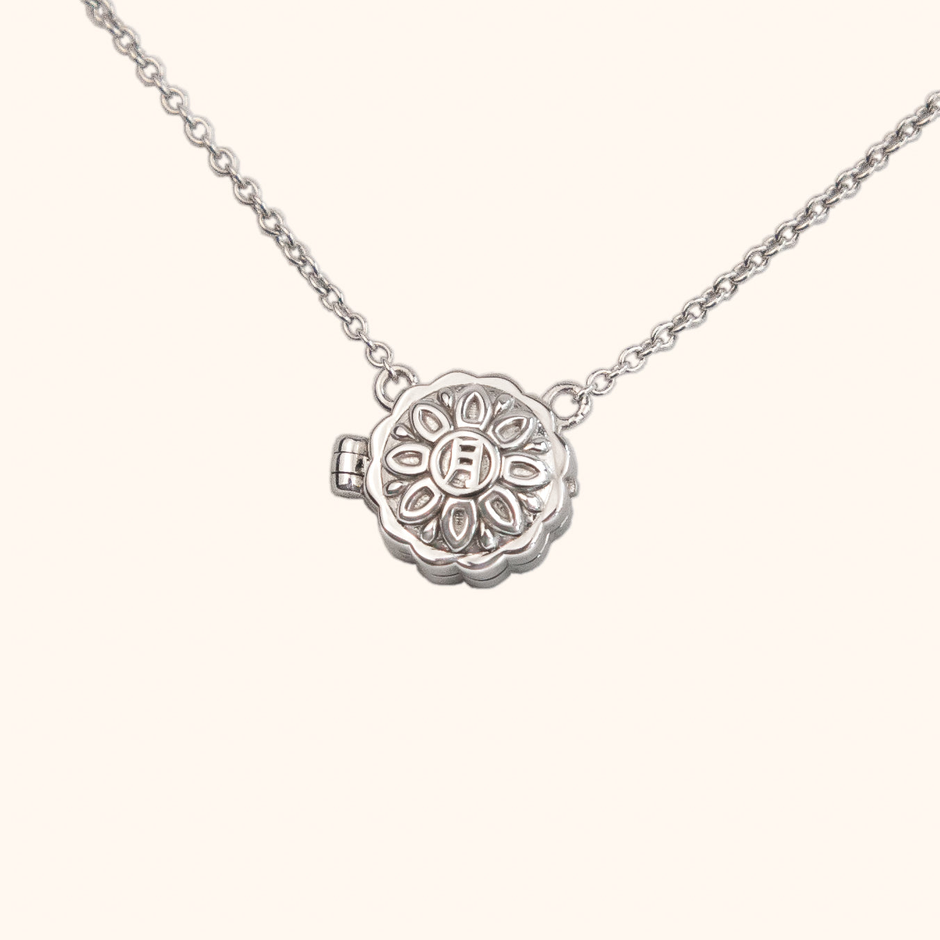 Mini Mooncake Locket in sterling silver. The locket has an intricate mooncake pattern with Chinese character for moon on the front.
